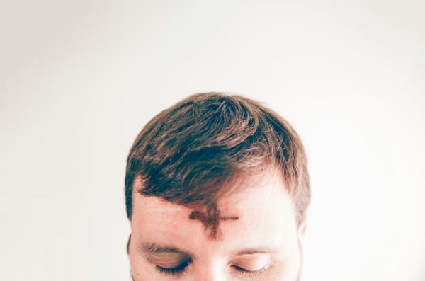 close up of ashes drawn in the shape of a cross on a young man's forehead